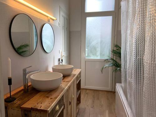 une salle de bain avec deux lavabos et deux miroirs dans l'établissement Maison 120m2 / centre ville / grand jardin 250m2, à Sète