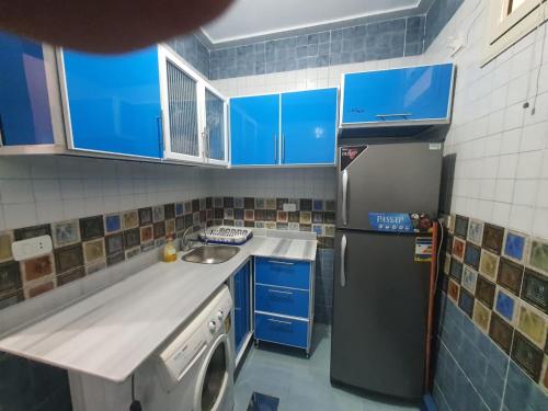 a kitchen with blue cabinets and a sink and a dishwasher at Abeer Suites 3 basement in Hurghada