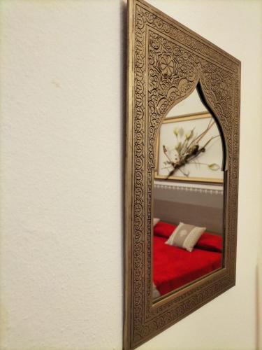 a mirror hanging on a wall with a red couch at B&B SHARDANA in Sennori