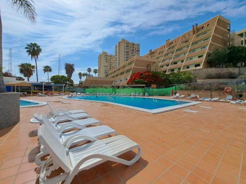 una fila di sedie a sdraio accanto alla piscina di Newly reformed apartment with sea view and pool, near the beach, in Playa de Las Americas a Playa de las Americas