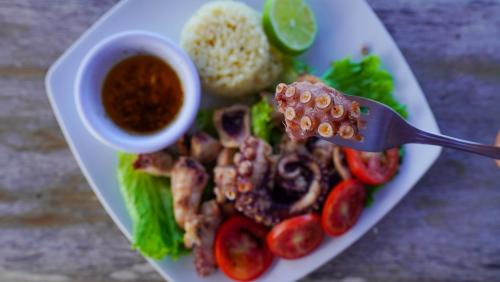 a plate of food with a fork with meat and vegetables at Hotel Rio Lagartos in Río Lagartos
