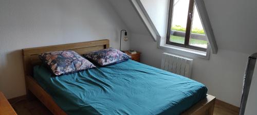 une chambre avec un lit avec des draps bleus et une fenêtre dans l'établissement Petite maison avec jardin à 400m de la plage, à Sarzeau