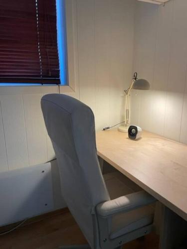 a desk with a chair next to a desk with a lamp at 4-mannsbolig sentralt i Auli 