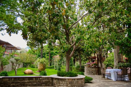 a garden with a table and chairs under a tree at Real Scampis Hotel in Elbasan