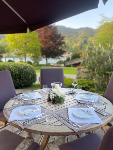 a wooden table with plates and silverware on it at Hotel Maier zum Kirschner in Rottach-Egern