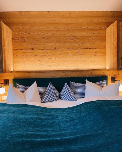 a bed with blue and white pillows on it at Hotel Maier zum Kirschner in Rottach-Egern