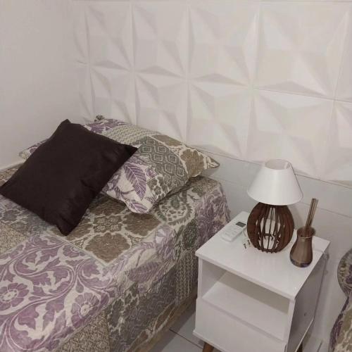 a room with a bed with a night stand and a lamp at Chalé 08 Porto dos Lençóis in Barreirinhas