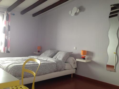 - une chambre avec des murs blancs et un lit avec une chaise jaune dans l'établissement LE GRAND ROUGET, à Beaucaire