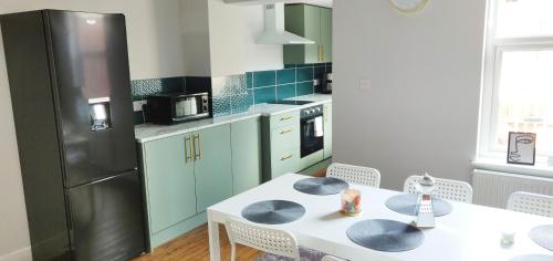 a kitchen with a white table and a refrigerator at Gilpin House in Leeds