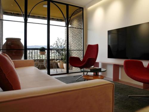 a living room with a couch and chairs and a tv at Loft Sotos de la Albolafia in Córdoba