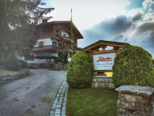 a house on a road with bushes in front of it at Hotel Maier zum Kirschner in Rottach-Egern