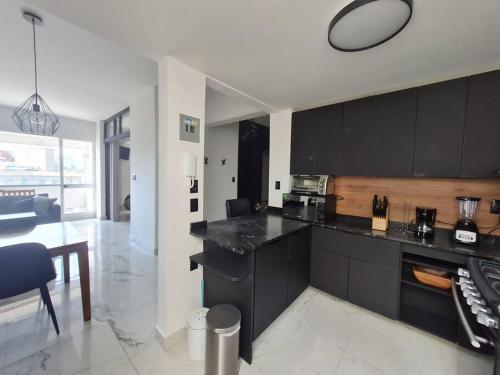 a kitchen with black cabinets and a dining room at Bright APT w/view near Reforma in Mexico City