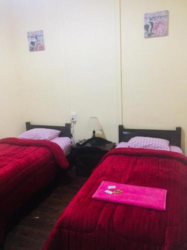 two beds in a room with a pink blanket on them at KORICANCHA in Lima