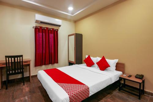 a bedroom with a bed and a desk with a red curtain at Boduppal in Hyderabad