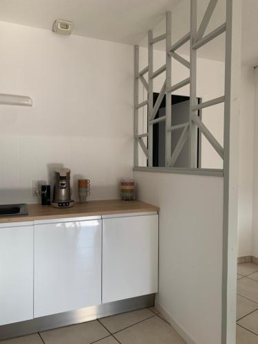 une cuisine avec des placards blancs et une échelle en métal dans l'établissement Appartement Chaleureux avec 2 grandes chambres, à Saint-Rambert-dʼAlbon