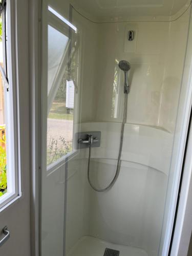 une douche dans une salle de bain avec une porte vitrée dans l'établissement Mobil home climatisé, à Lège-Cap-Ferret