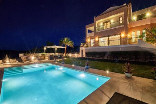 una piscina frente a una casa por la noche en Luxury Villa Argi infinity private pool, en Kissamos