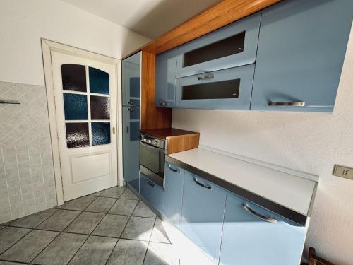 a small kitchen with blue cabinets and a window at Villetta S'Arenada in Golfo Aranci