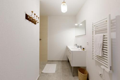 een witte badkamer met een wastafel en een spiegel bij Clara YourHostHelper in Montauroux