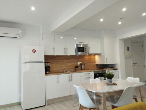 - une cuisine blanche avec une table et un réfrigérateur blanc dans l'établissement Apartamento Rodhes playa 2-A5, à Roses