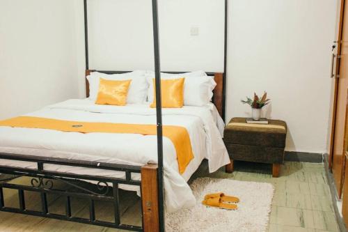 sypialnia z dużym łóżkiem z pomarańczowymi i białymi poduszkami w obiekcie Kwe Decasa w mieście Kisumu