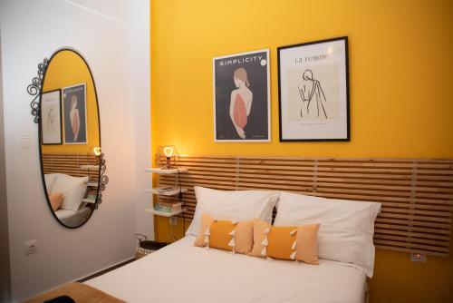 een slaapkamer met een bed met oranje muren en een spiegel bij Retro Boutique Apt W Balcony in Historical Area in Thessaloniki