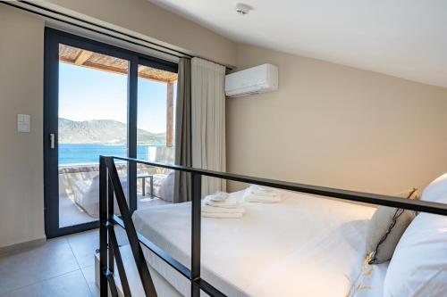 1 Schlafzimmer mit einem Bett und einem Balkon mit Meerblick in der Unterkunft Elivia Boutique Suites in Almiropótamos