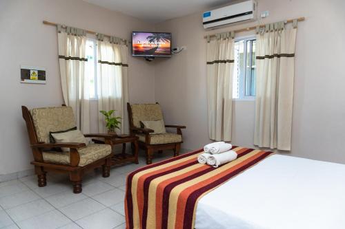 a bedroom with a bed and two chairs and a tv at Narcizo in Lules