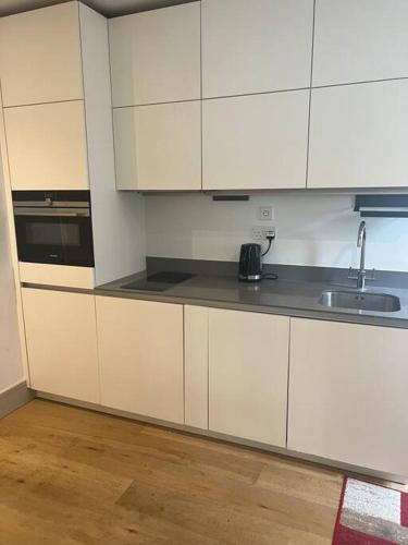 a kitchen with white cabinets and a sink at 1 bed Apartment in Whitechapel in London