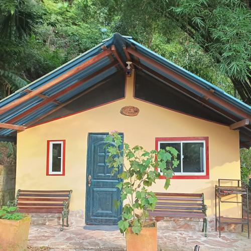 ein kleines Haus mit zwei Bänken davor in der Unterkunft Nido de Pajaros in Portachuelo