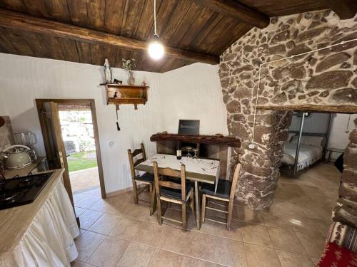 eine Küche mit einem Tisch und einer Steinmauer in der Unterkunft Muristene Pozzo Santa Cristina in Paulilatino