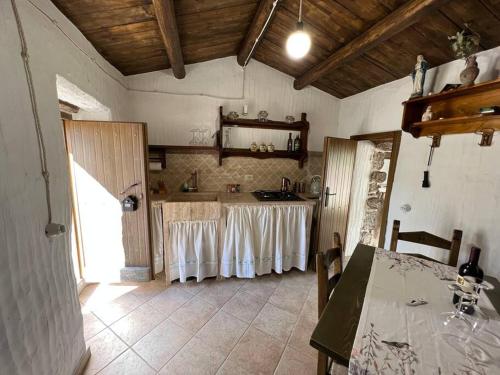 eine Küche mit einem Tisch und weißen Vorhängen in der Unterkunft Muristene Pozzo Santa Cristina in Paulilatino