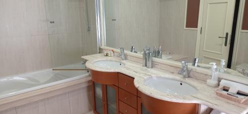 een badkamer met 2 wastafels en een grote spiegel bij CABANAS 1ª LINEA PLAYA in Cabañas