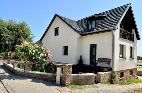 uma casa branca com um banco numa parede de retenção em L’Escale em Riquewihr