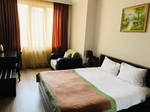 a hotel room with a bed and a desk and a chair at Hotel Brighton in Batumi