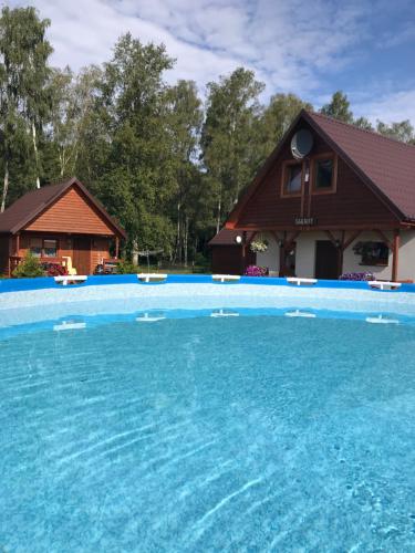 a large swimming pool with a house in the background at KANZAS in Jarosławiec