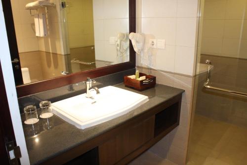 Varna Culture Hotel Soerabaia في سورابايا: حمام مع حوض ومرآة ودش