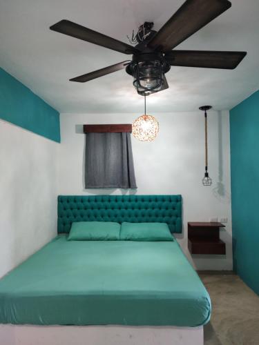 1 dormitorio con cama verde y ventilador de techo en Le Blue Coast en Progreso