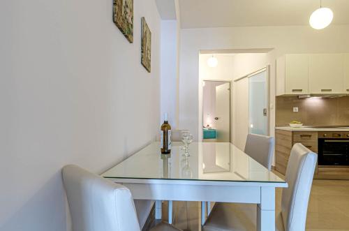 a dining room with a glass table and white chairs at Palapart Gikas Gouvia in Gouvia