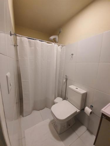 uma casa de banho branca com um WC e um chuveiro em Suítes B6 em Porto de Galinhas