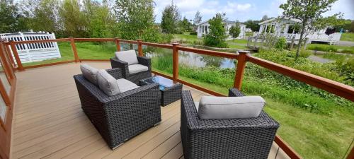 a deck with two wicker chairs and tables on it at Bluebell Luxury 2 Bedroom Lodge at Southview Holiday Park in Skegness