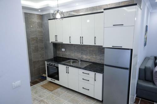 una cocina con armarios blancos y fregadero en Fishta Apartments Q5 33, en Velipojë
