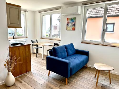 un salon avec un canapé bleu et une cuisine dans l'établissement L’Escale, à Riquewihr