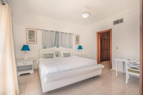 - une chambre blanche avec un lit blanc et un bureau dans l'établissement Modern Penthouse Near The Beach Long Term Deal, à Punta Cana