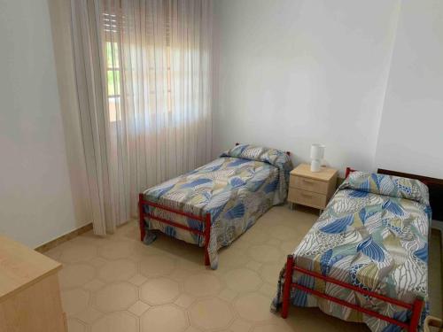 a bedroom with two beds and a table and a window at Casa Vacanza Torre di Mezzo - Alba in Marausa