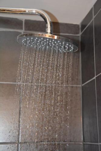 une douche avec de l'eau qui en sort dans une salle de bain dans l'établissement Stijlvol 4-kamerappartement in Valmorel aan de piste, à Valmorel