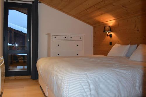 - une chambre avec un lit blanc et une fenêtre dans l'établissement Stijlvol 4-kamerappartement in Valmorel aan de piste, à Valmorel