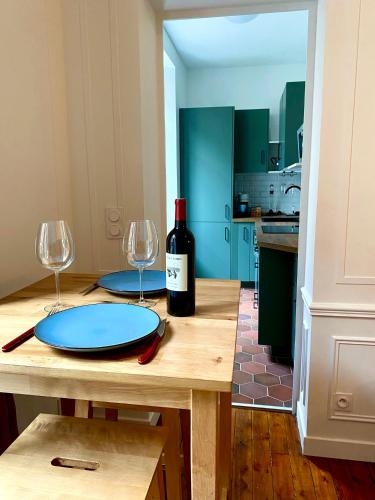 a table with a bottle of wine and two glasses at Charmant appartement Rouen centre in Rouen