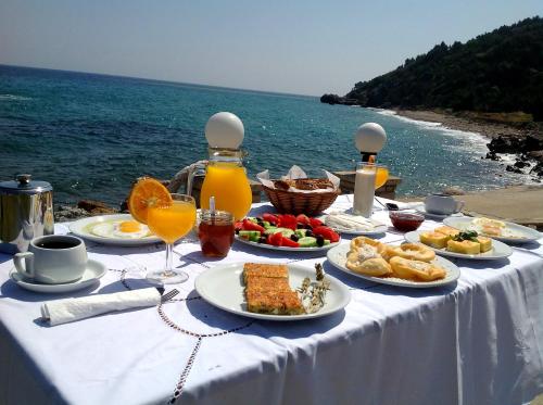 een tafel met borden en uitzicht op de oceaan bij Violetta Seaside Studios&Apartments in Karlovasi