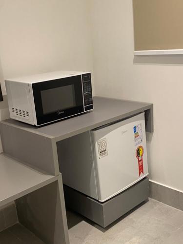 a microwave sitting on top of a counter with a refrigerator at Arpoar Suítes - Suíte 433 in João Pessoa